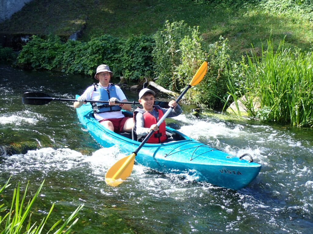 tata z synem płyną kajakiem po bystrzu