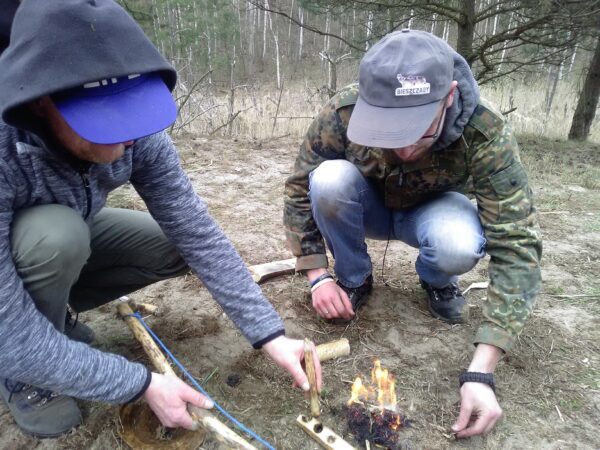 Rozpalanie ognia łukiem ogniowym na szkoleniu survivalowym