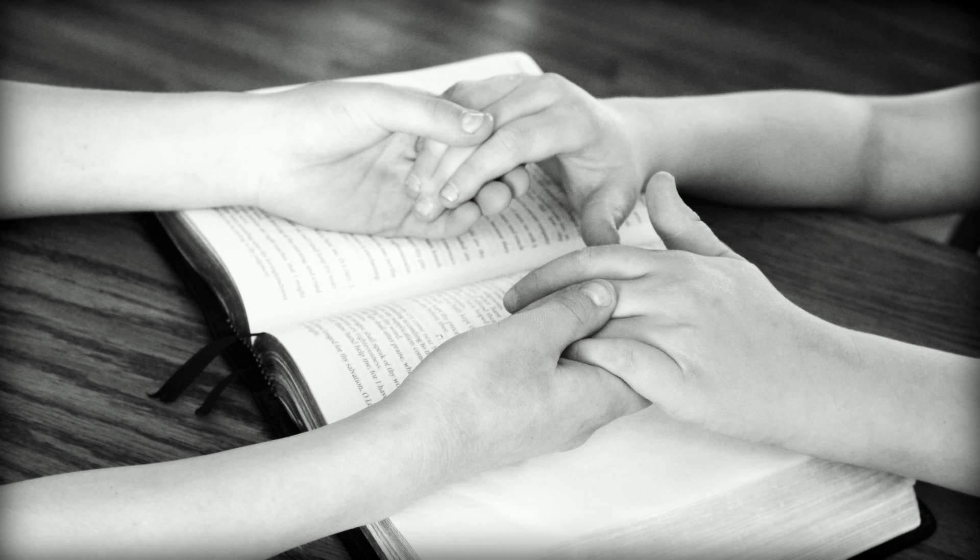 Trzymające się ręce ojca i dziecka położone na Biblii