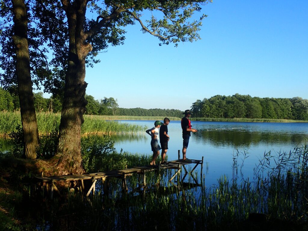 Tata z dziećmi łowią ryby na biwaku nad jeziorem